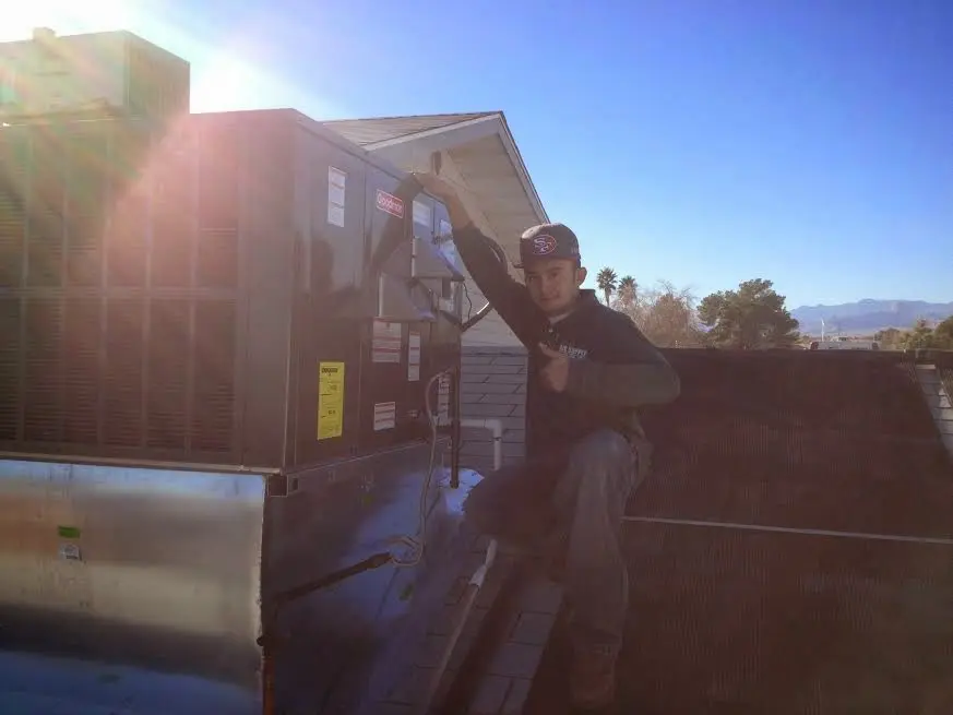 HVAC technician performing AC Tune-Up on a rooftop unit in Madisonville