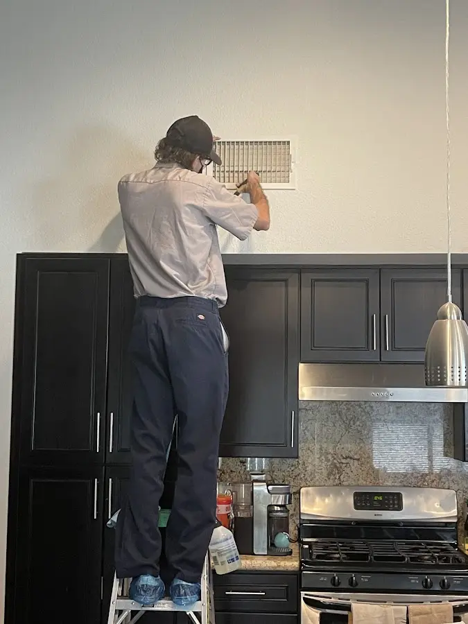 Technician inspecting an air vent during HVAC service in Madisonville